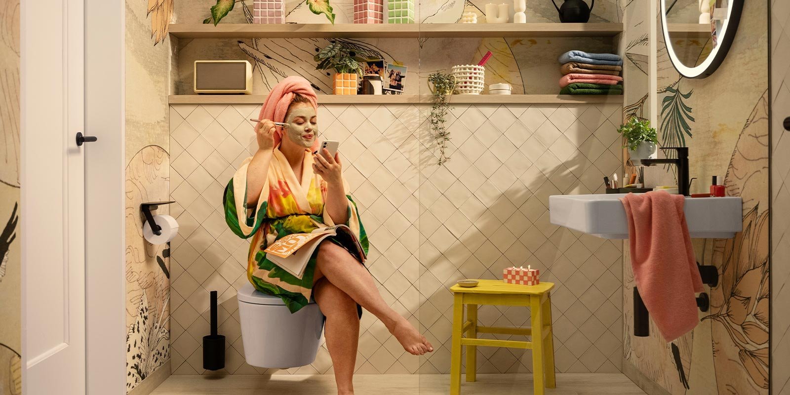 Eine Frau mit einer Gesichtsmaske sitzt entspannt auf der Toilette und schaut auf ihr Handy, während sie ein Magazin hält.